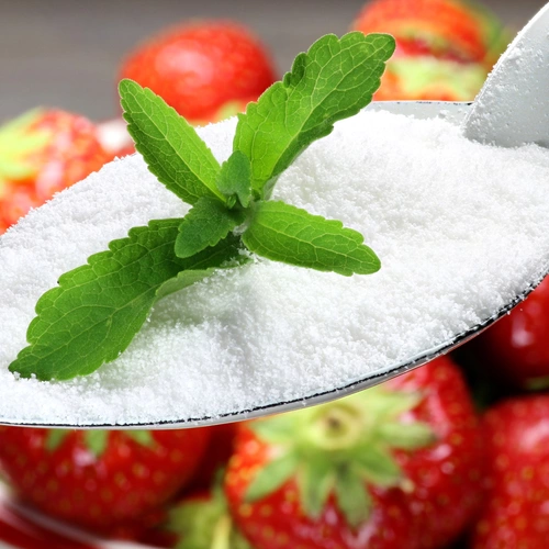 Ein Löffel mit weißem Pulver liegt neben frischen Erdbeeren. Ein grünes Blatt des Süßkrauts (Stevia rebaudiana) ist auf dem Pulver, was eine natürliche Süßungsoption hervorhebt.