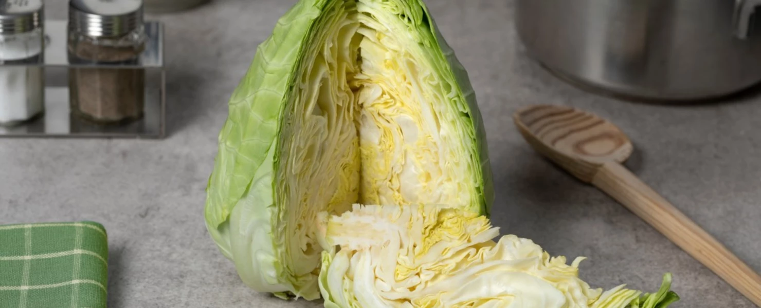 Aufgeschnittener Spitzkohl auf einer Küchenarbeitsfläche mit Kochutensilien.