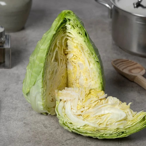Aufgeschnittener Spitzkohl auf einer Küchenarbeitsfläche mit Kochutensilien.