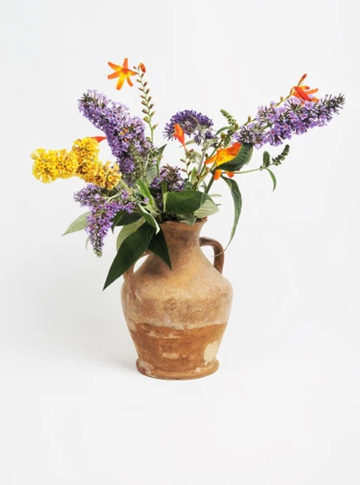 Ein rustikaler Krug mit einem Sommerblumenstrauß aus Buddleja und anderen Gartenblumen.