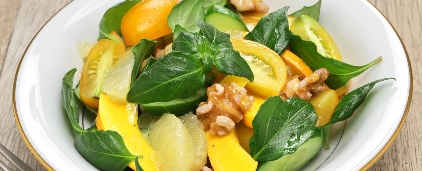 Pilzkraut (Plectranthus amboinicus) in einem frischen Salat mit Mango, Walnüssen und verschiedenen Gemüsesorten, der in einer weißen Schale angerichtet ist.
