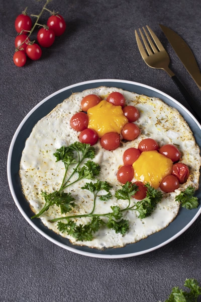 Ein Teller mit Rührei, garniert mit frischer Krauser Petersilie (Petroselinum crispum), Cherrytomaten und einer Prise Gewürzen. Das Gericht ist ansprechend angerichtet und bietet eine frische, gesunde Mahlzeit.